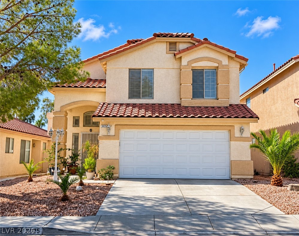 Two-story stucco house with a red tile roof, double garage, and desert landscaping.