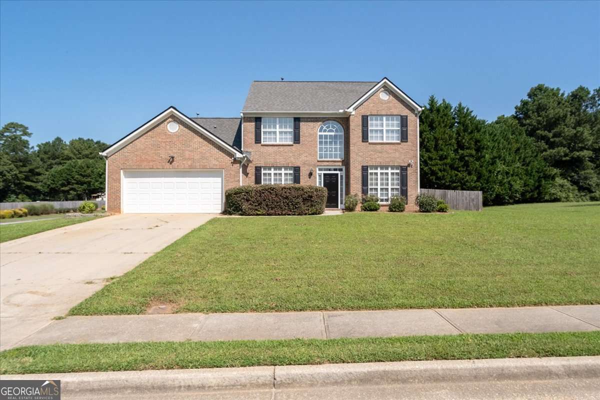 Two-story brick house with an attached garage, broad lawn, and driveway.