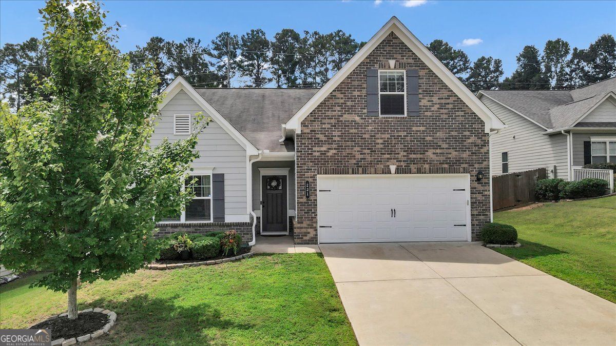 Suburban house with a brick gable, attached double garage, and broad driveway.