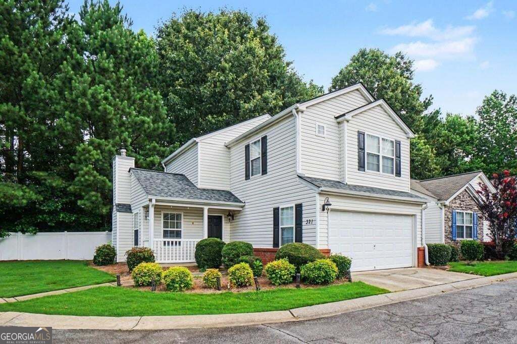 Two-story white house with a covered porch, attached garage, and landscaped front yard.
