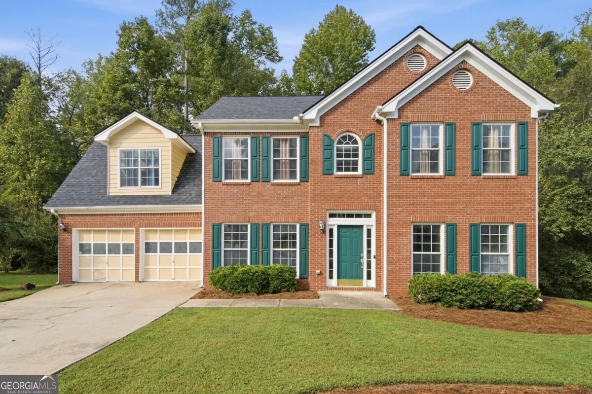 Two-story brick house with teal shutters, an attached double garage, and a front lawn.