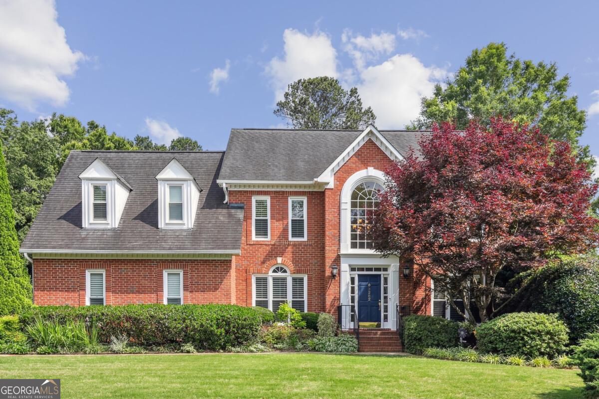 Red brick house with white dormers, a large arched window, and a blue front door.
