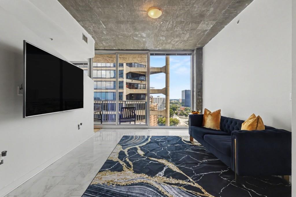 Apartment living room with navy sofa, striking marble-pattern rug, and expansive city-facing windows.