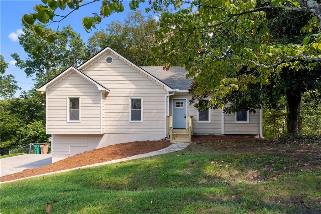 Beige house with a blue front door and small entry porch, set among mature trees.