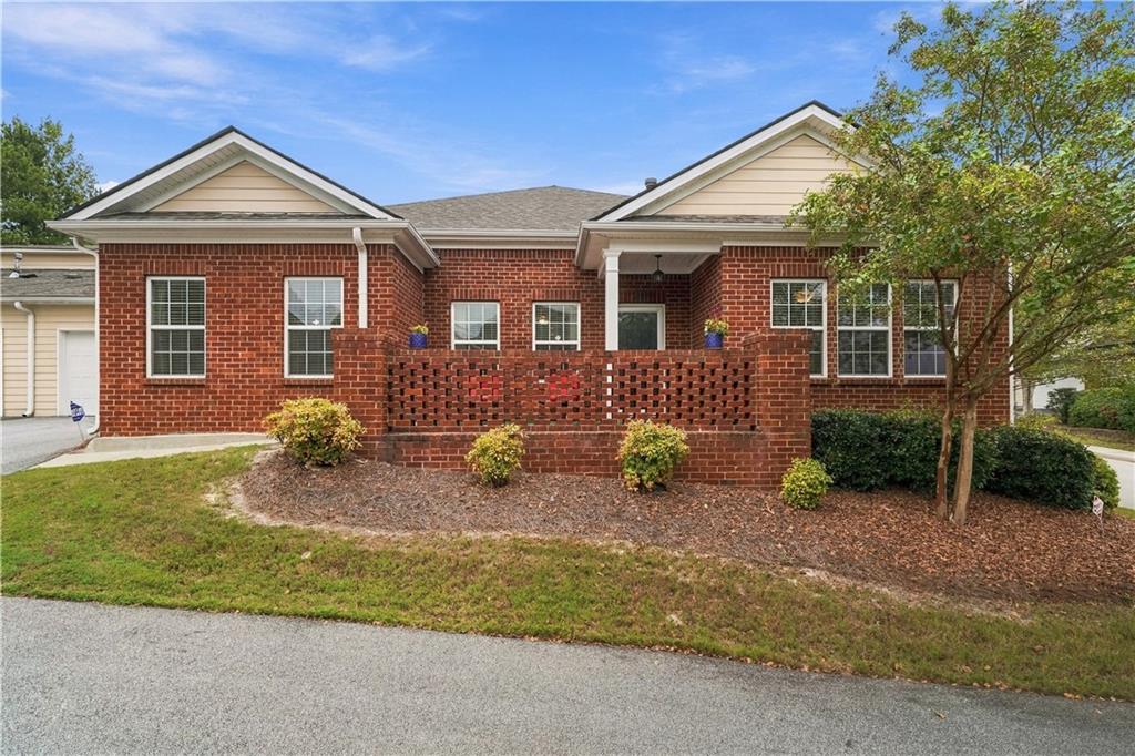 Rear of a red brick home with a covered patio, low brick wall, and landscaped yard.