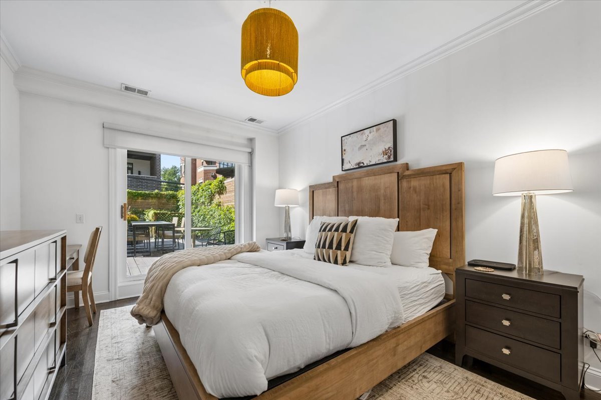Staged bedroom with a wooden bed and sliding glass doors to a patio.