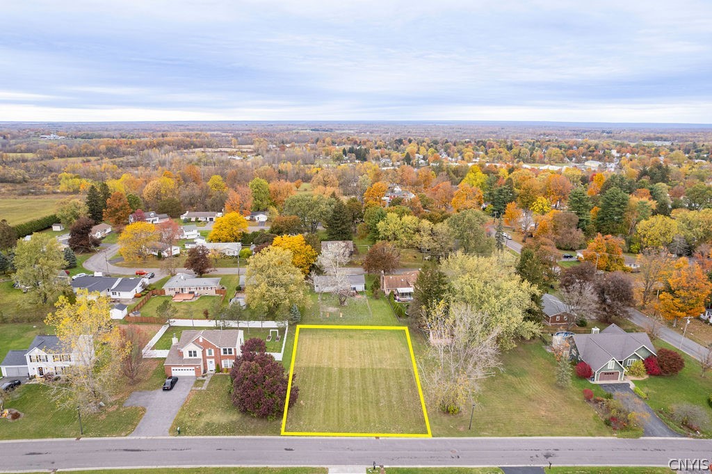 Vacant residential lot outlined in yellow beside Port Street, with homes and autumn trees nearby.