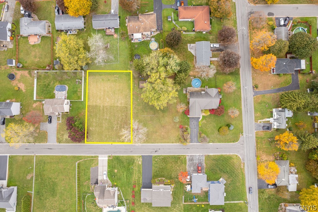 Aerial view of a vacant residential lot outlined in yellow along a neighborhood street.