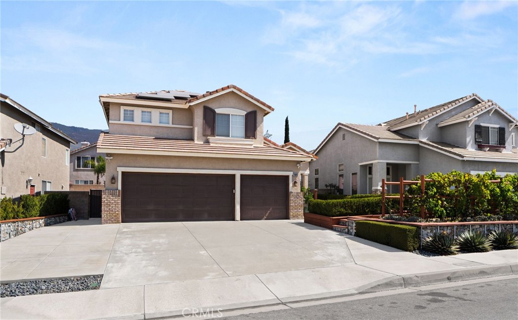 Two-story suburban home with a wide concrete driveway, two garage doors, and landscaped front yard.