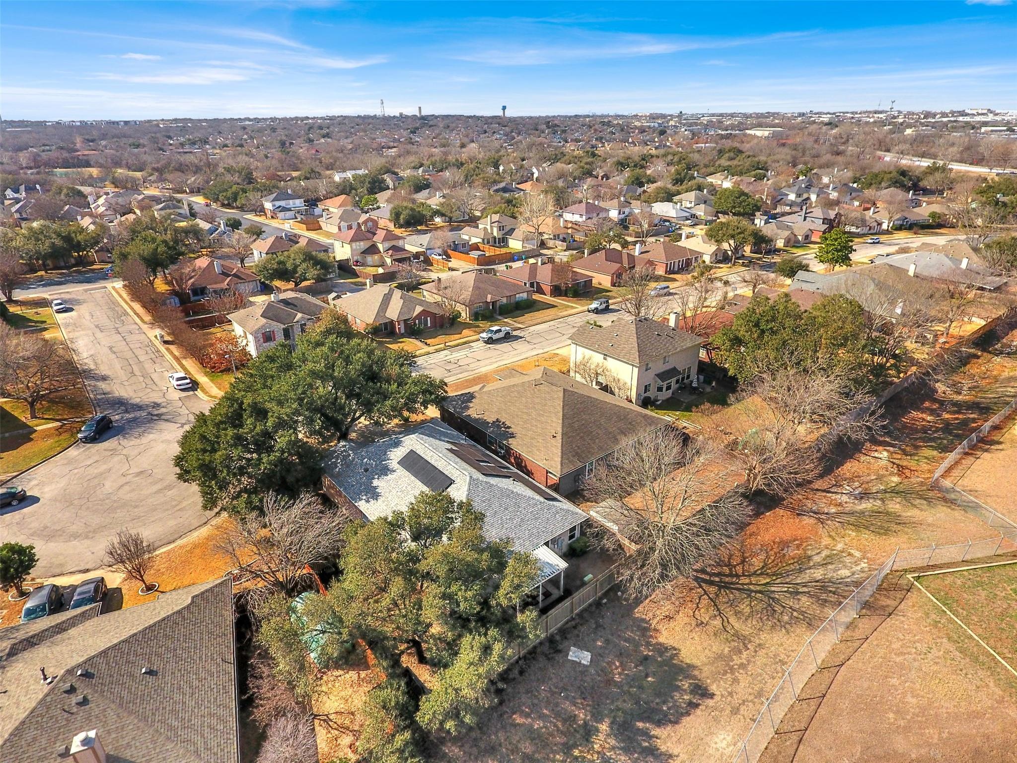 Aerial view of a residential neighborhood with tree-lined streets and a fenced open area.