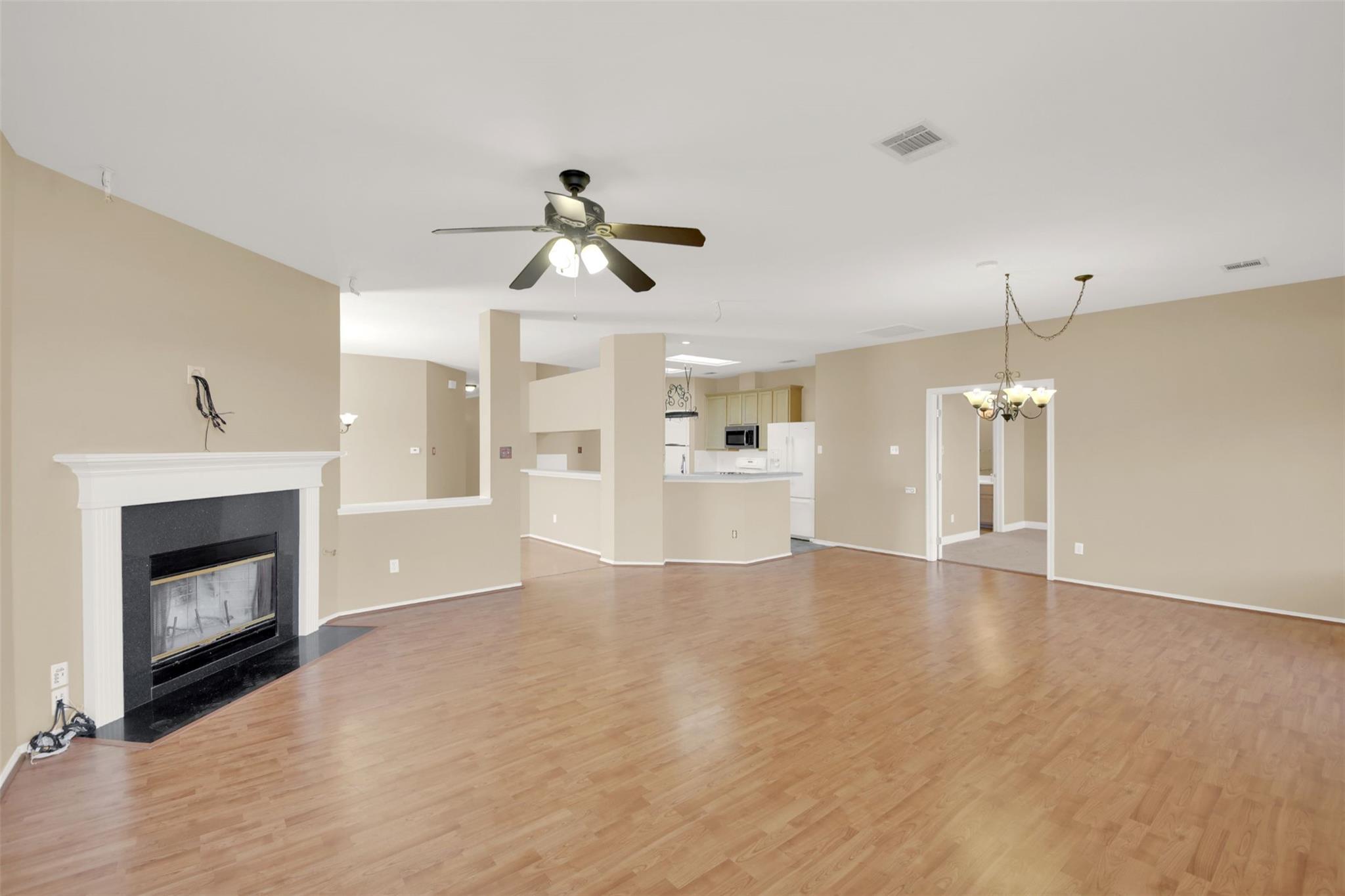 Open living and dining area with wood floors, a fireplace, and a kitchen breakfast bar.