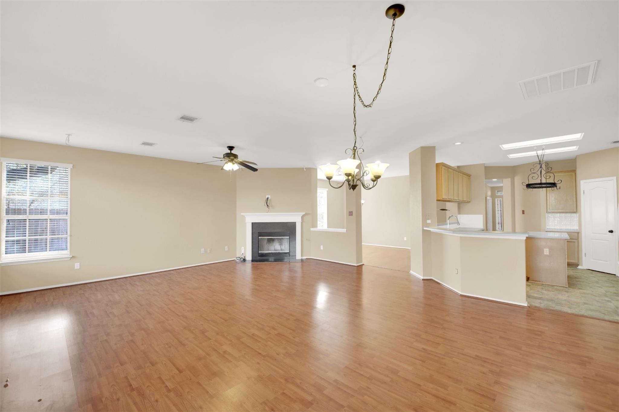 Open living and dining area with wood floors, fireplace, and kitchen breakfast bar.