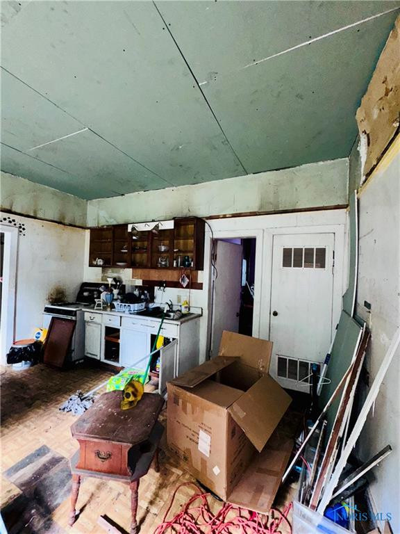 Cluttered, worn kitchen with white cabinets, dark wood cupboards, and an open box.