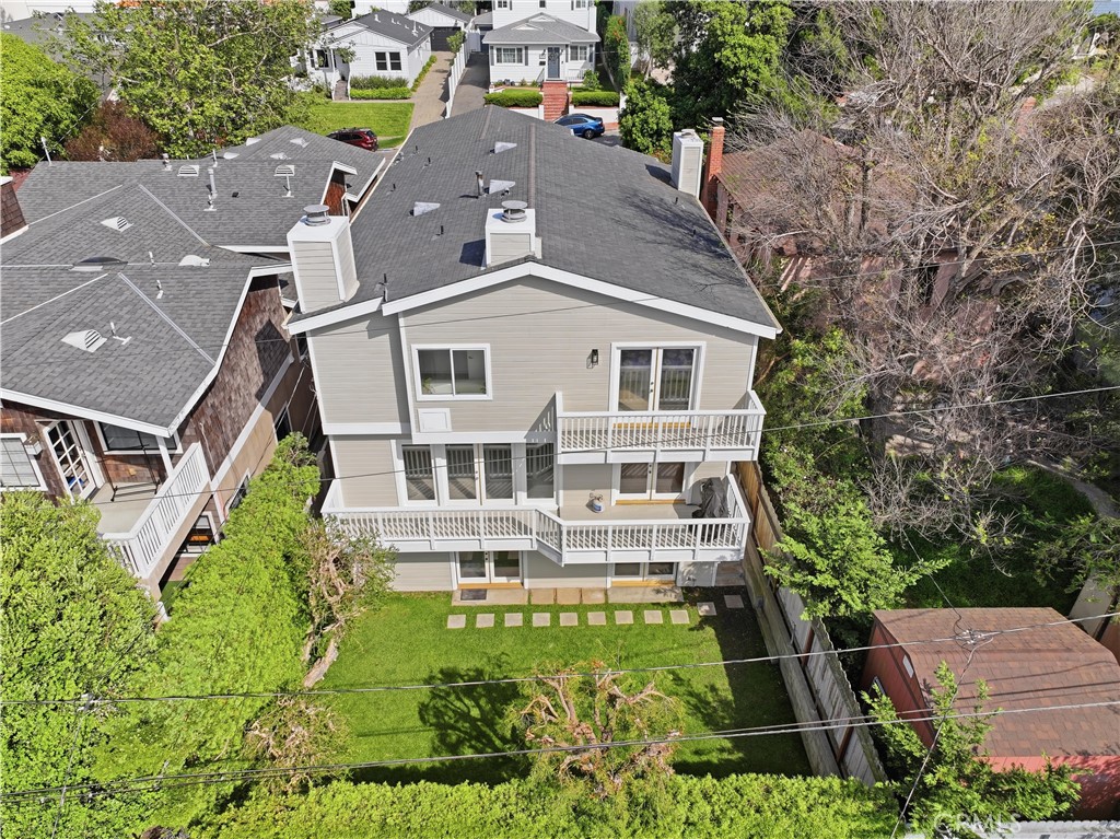 Aerial view of a two-story gray home with white balconies and a fenced backyard.