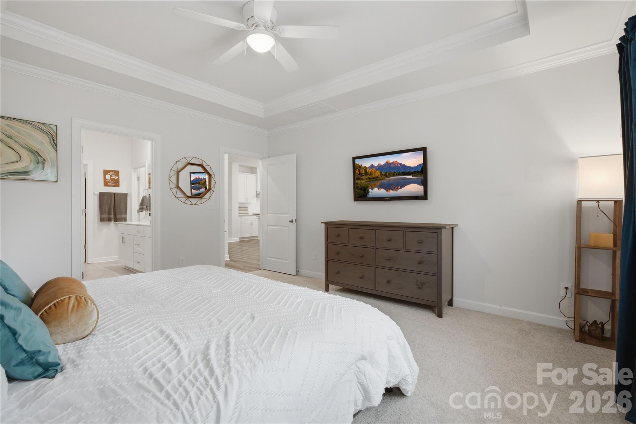 Bedroom with a white quilted bed, teal pillows, and a dark wood dresser.