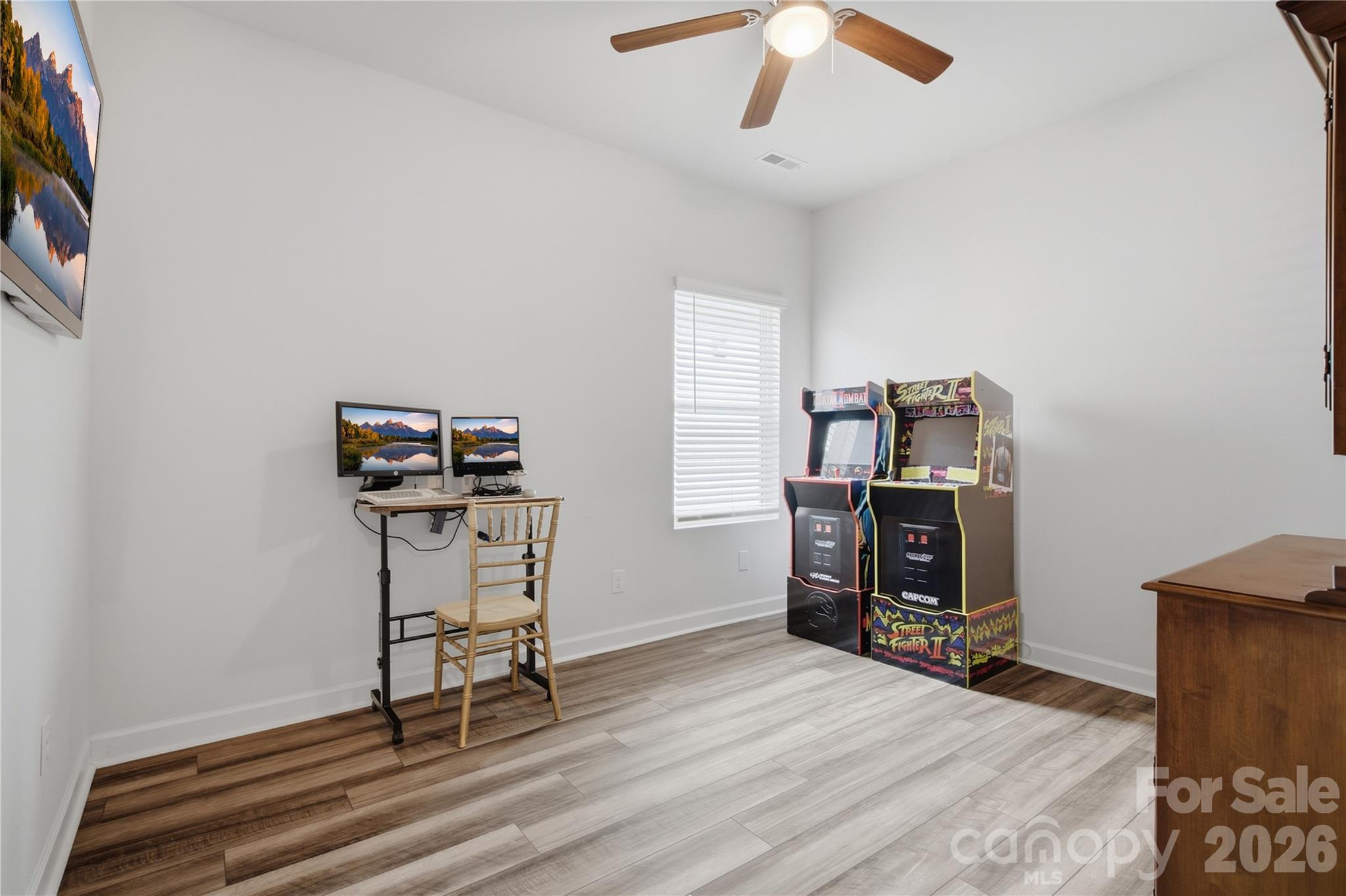 Home office and game room with two arcade cabinets and a computer desk.