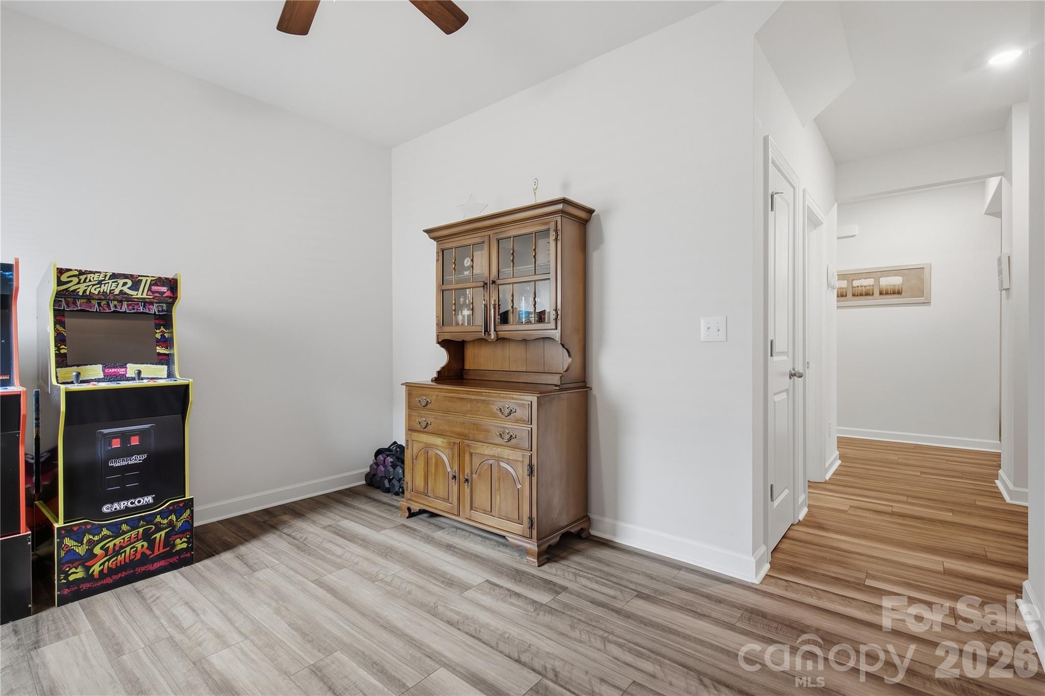 Bonus room with a Street Fighter II arcade cabinet, wooden hutch, and gray tile flooring.