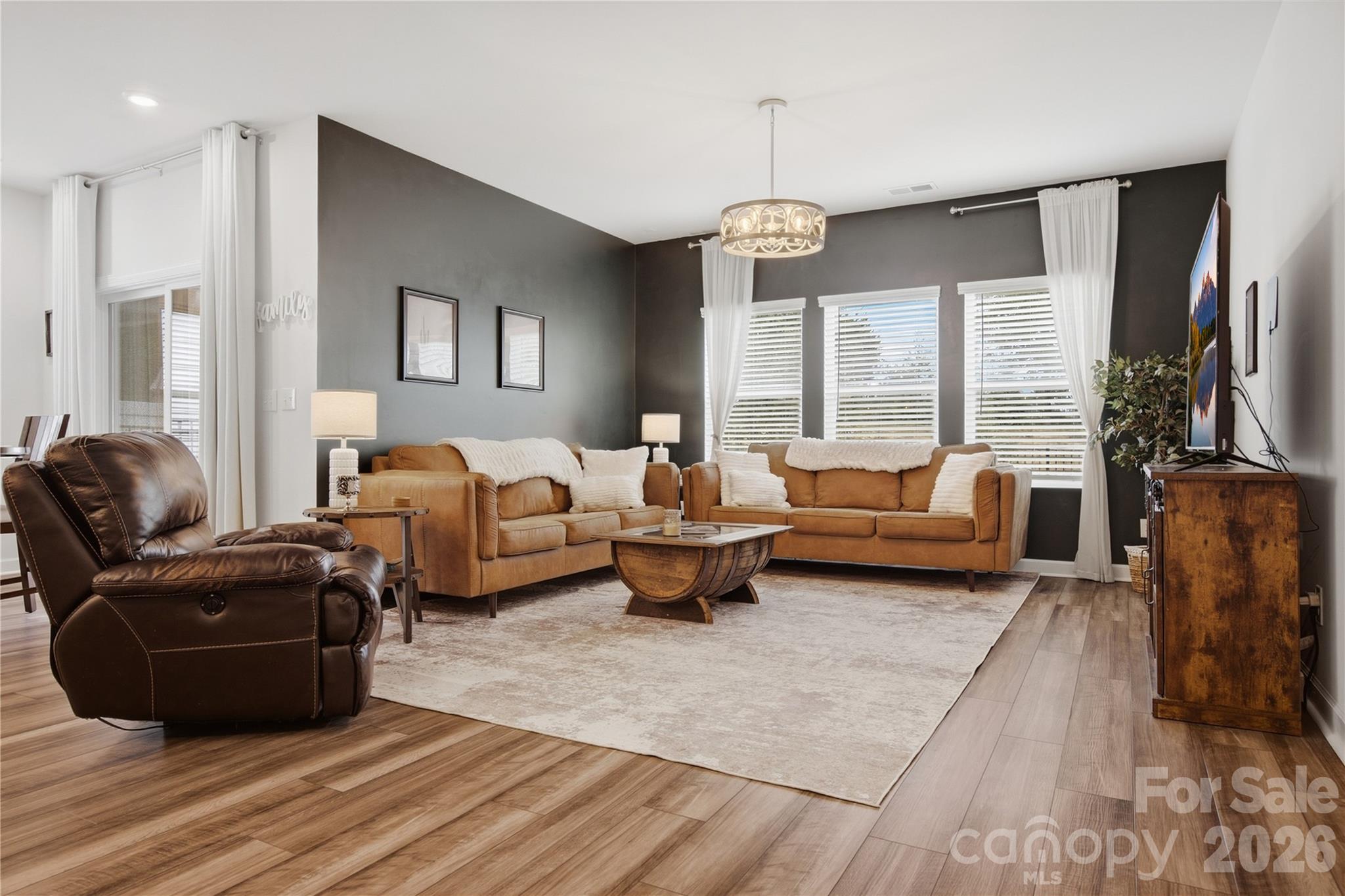 Living room with tan sofas, a dark leather recliner, and a round wood coffee table.