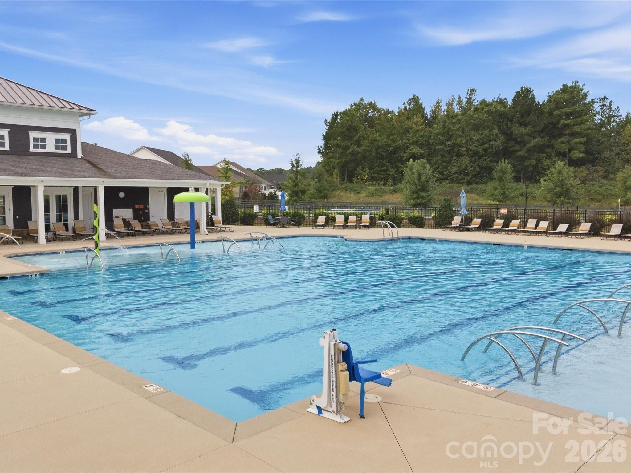 Community swimming pool with an accessible lift, lounge chairs, and a covered poolside pavilion.