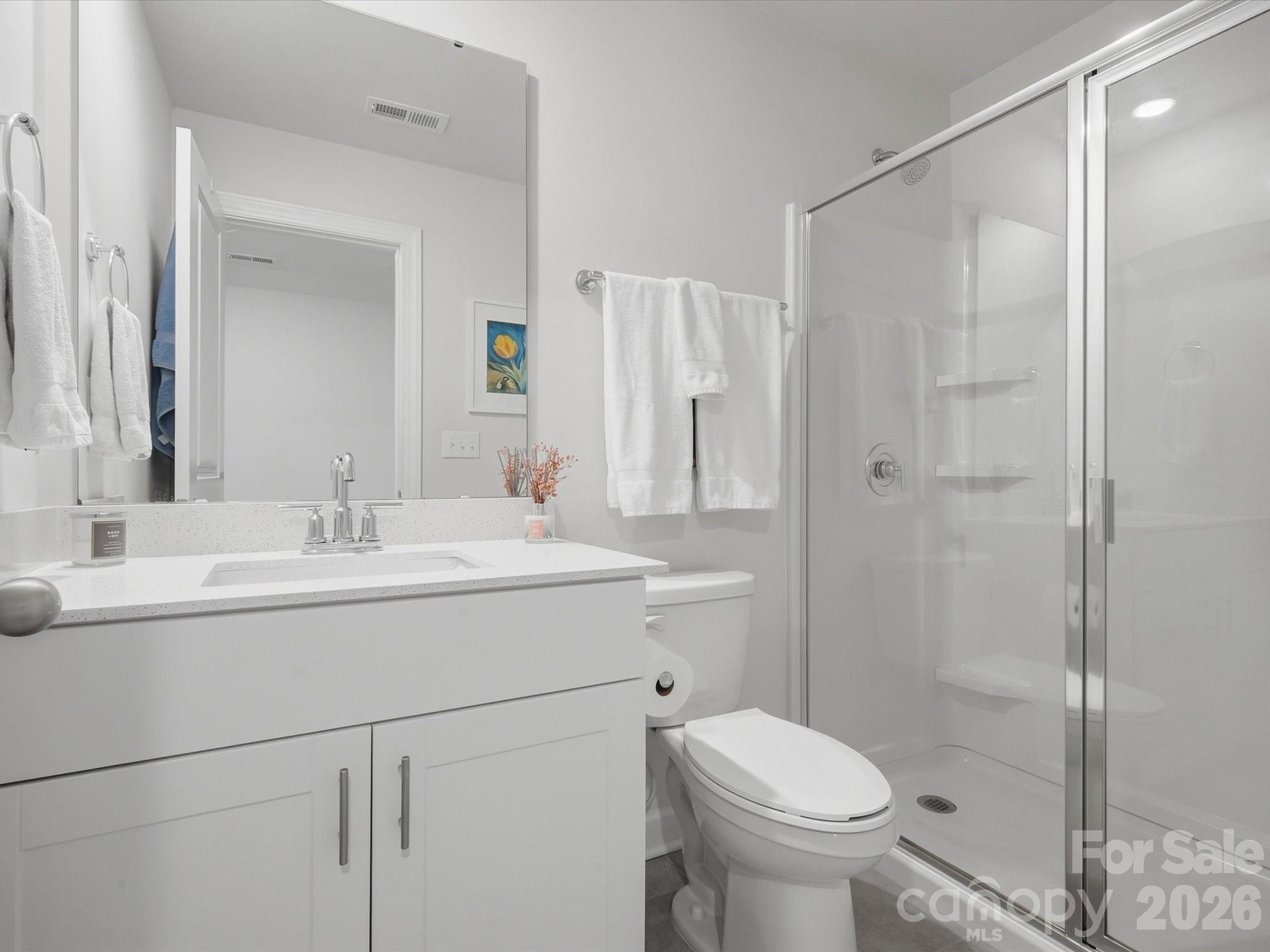 Bathroom with a white vanity, toilet, and glass-enclosed shower.