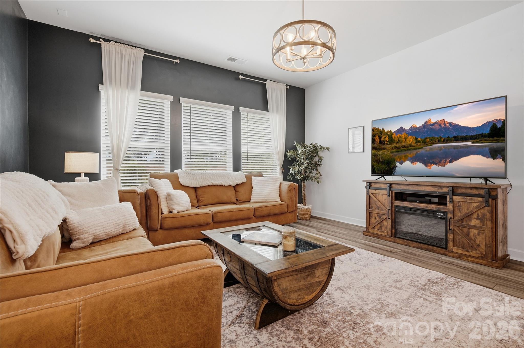 Living room with tan sofas, a rustic wood coffee table, and a television on a barn-door-style console.