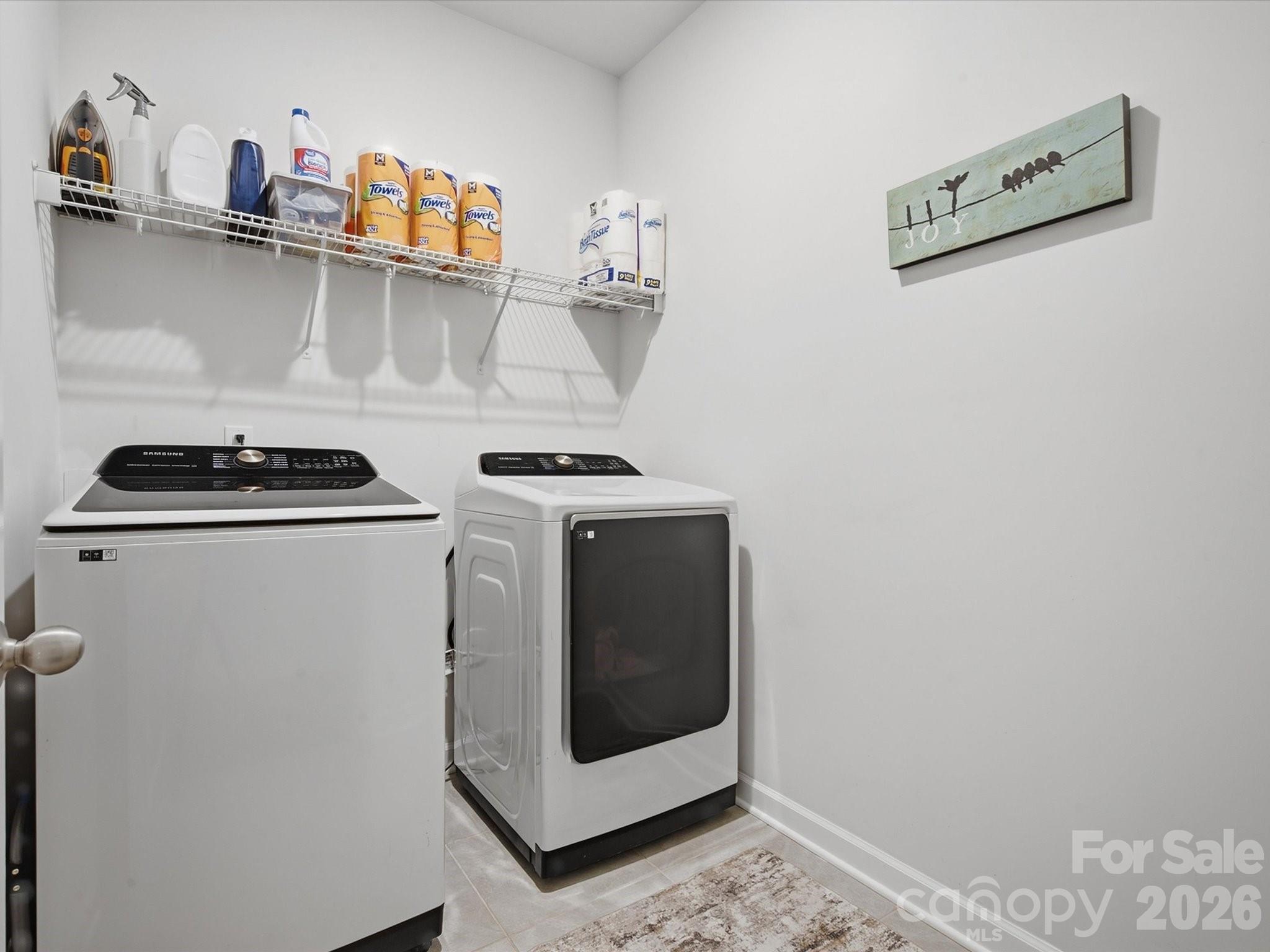 Laundry room with a top-load washer, front-load dryer, and wall-mounted wire shelf.