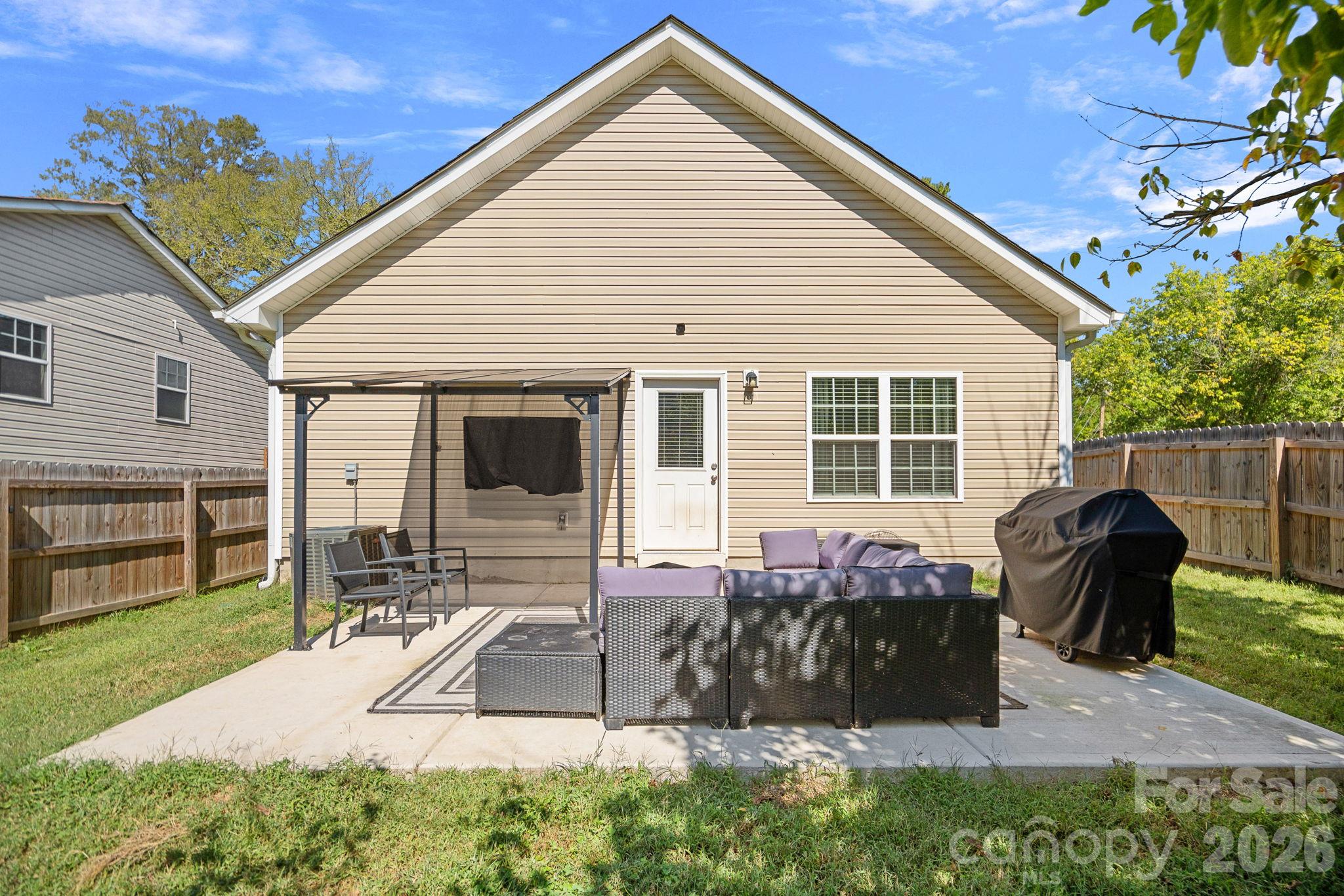 House’s rear patio with outdoor seating, a metal awning, and a covered grill.