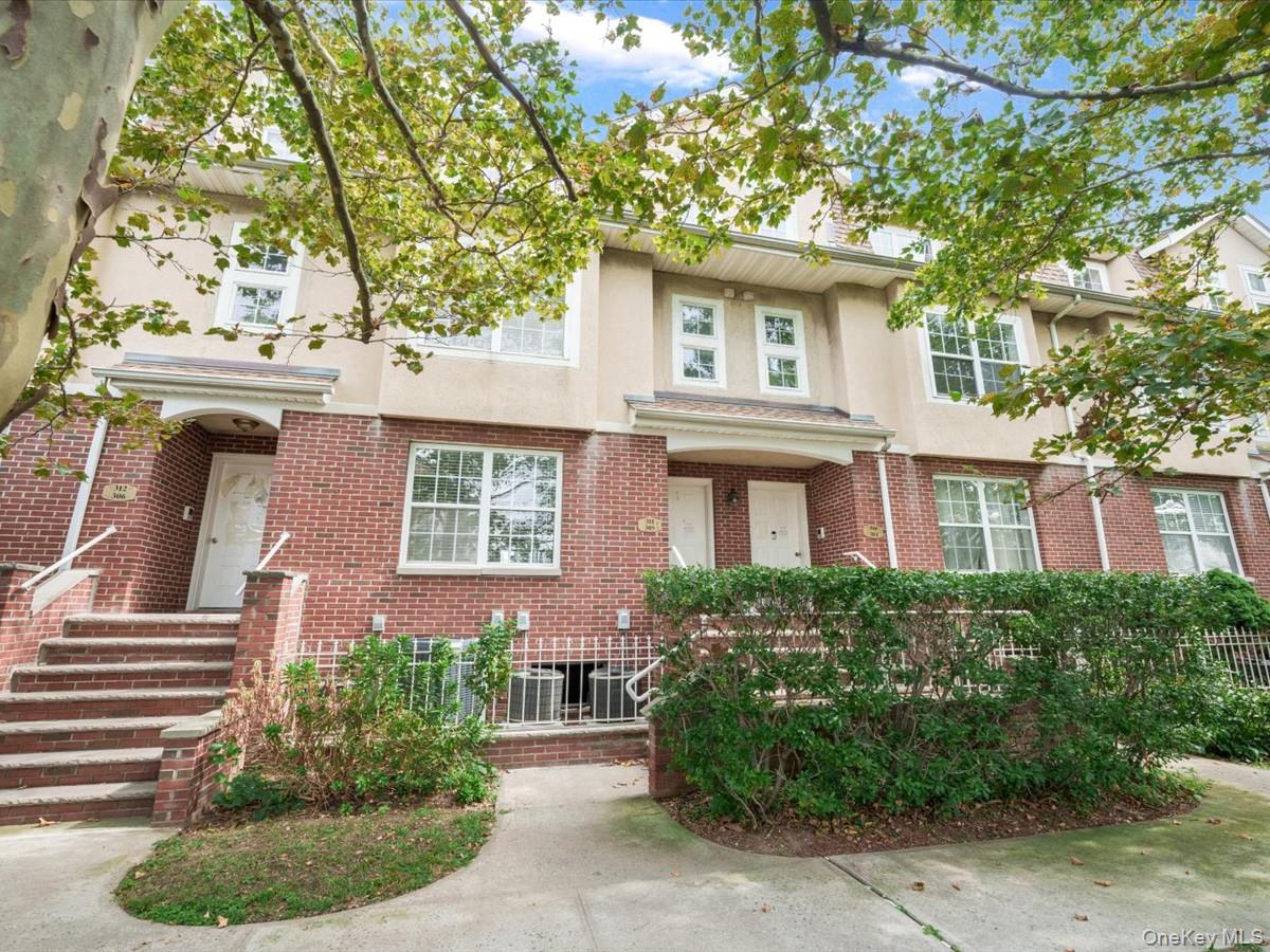 Attached brick-and-stucco townhomes with front steps and leafy trees.