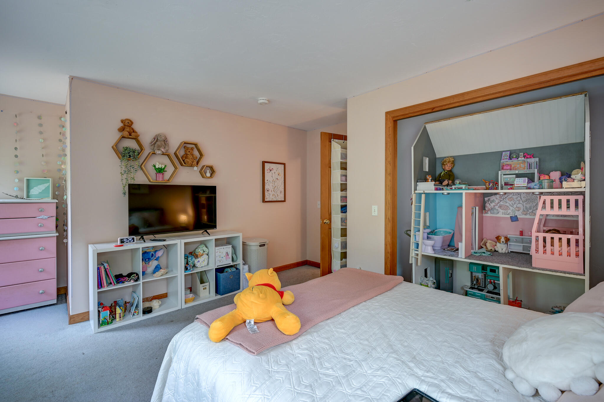 Bedroom with white bed, pink dresser, and an elaborate built-in dollhouse play area.
