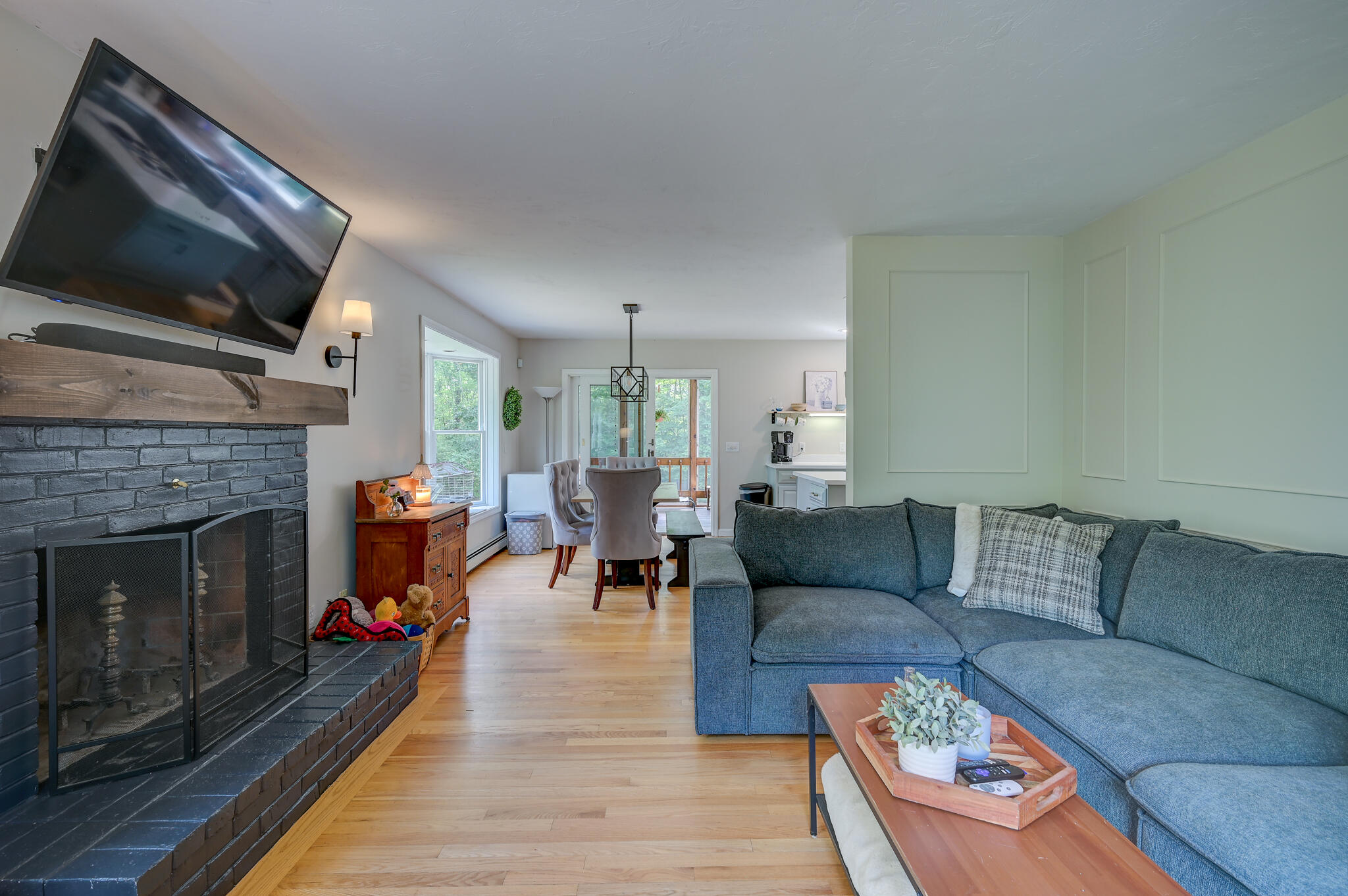 Living room with a blue sectional, brick fireplace, and dining area leading to glass doors.