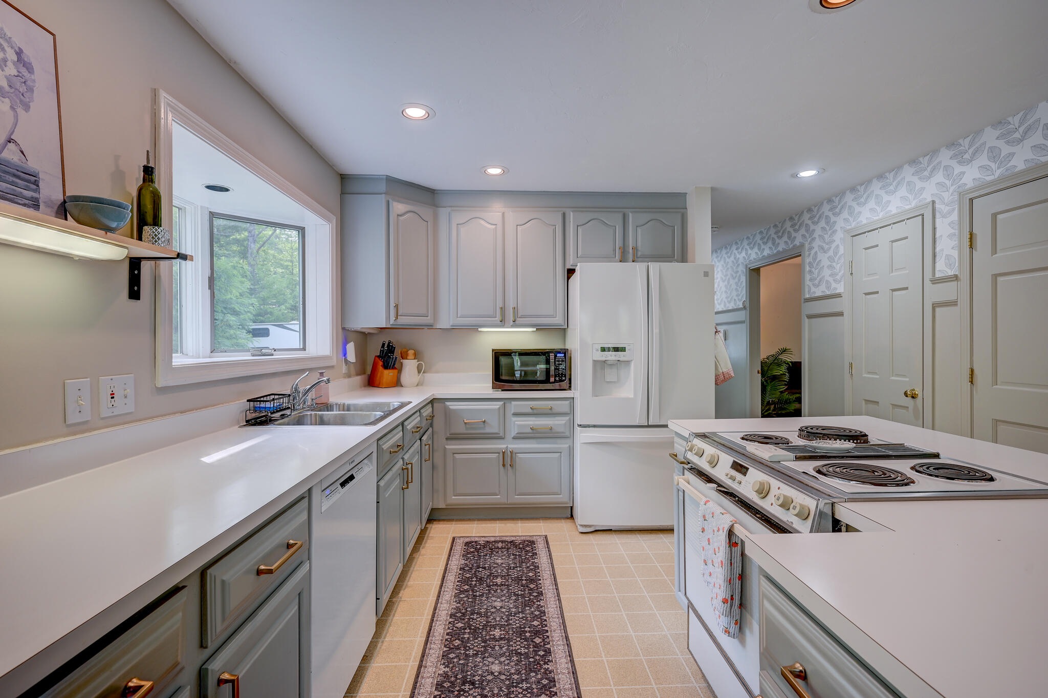 Kitchen with gray cabinets, white appliances, a large window, and a central electric range.