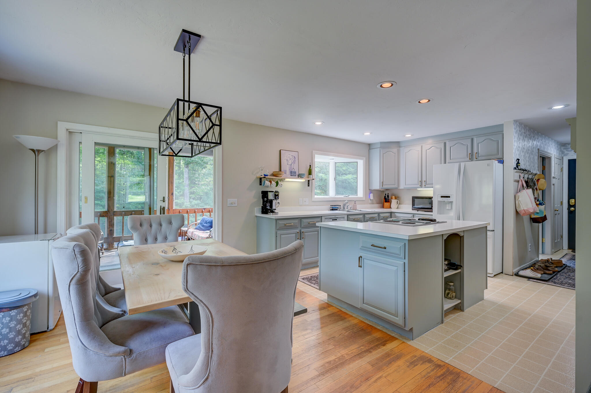 Open kitchen and dining area with a central island, pale blue cabinets, and sliding doors to a deck.
