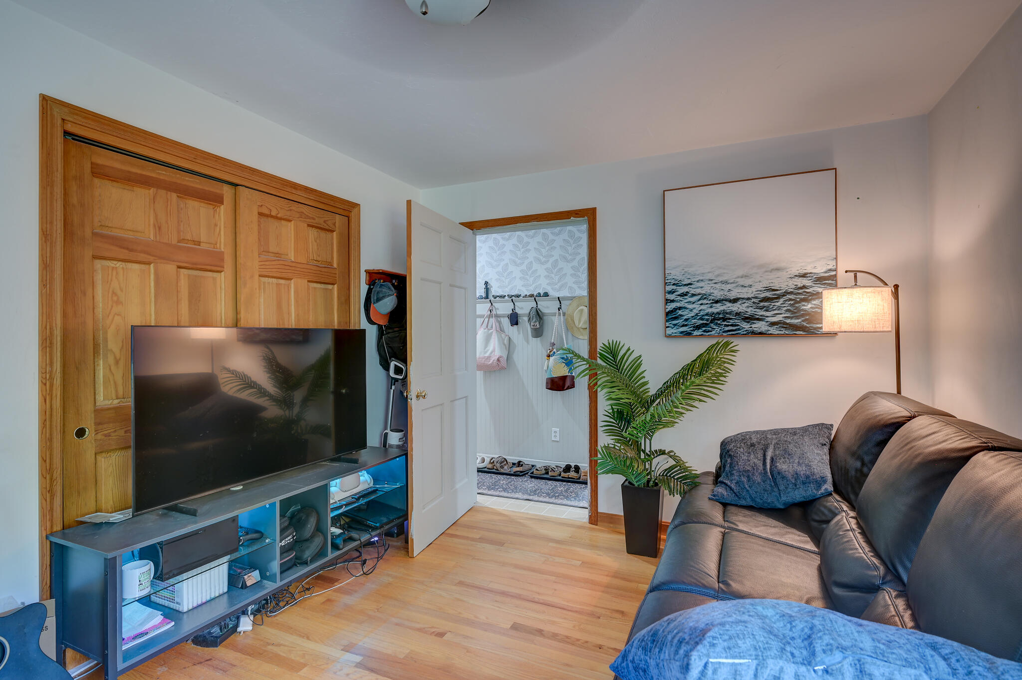 Living room with a leather sofa, TV, and an open doorway to a mudroom.