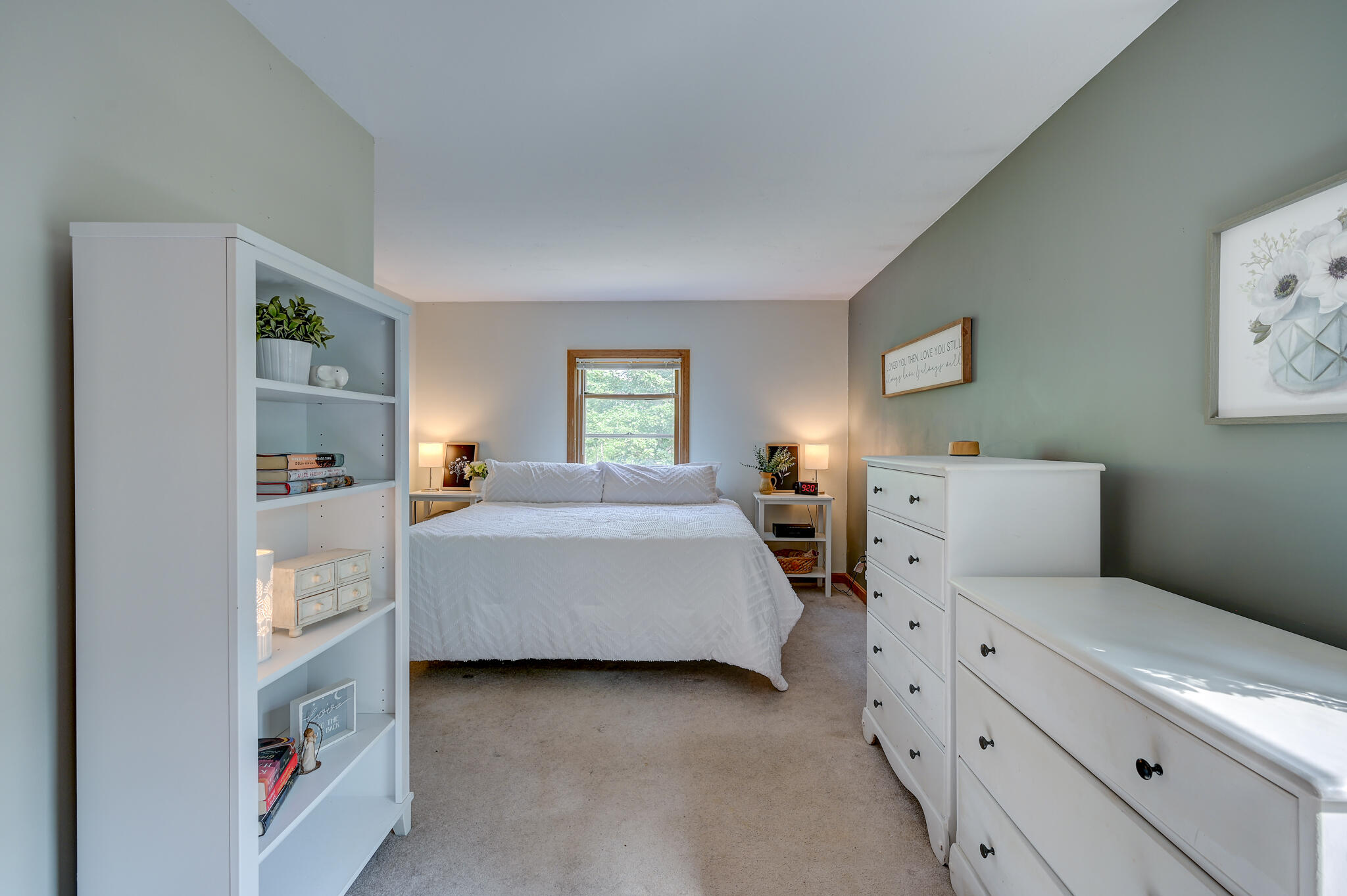 Bedroom with a white bed, built-in shelving, and matching dressers.