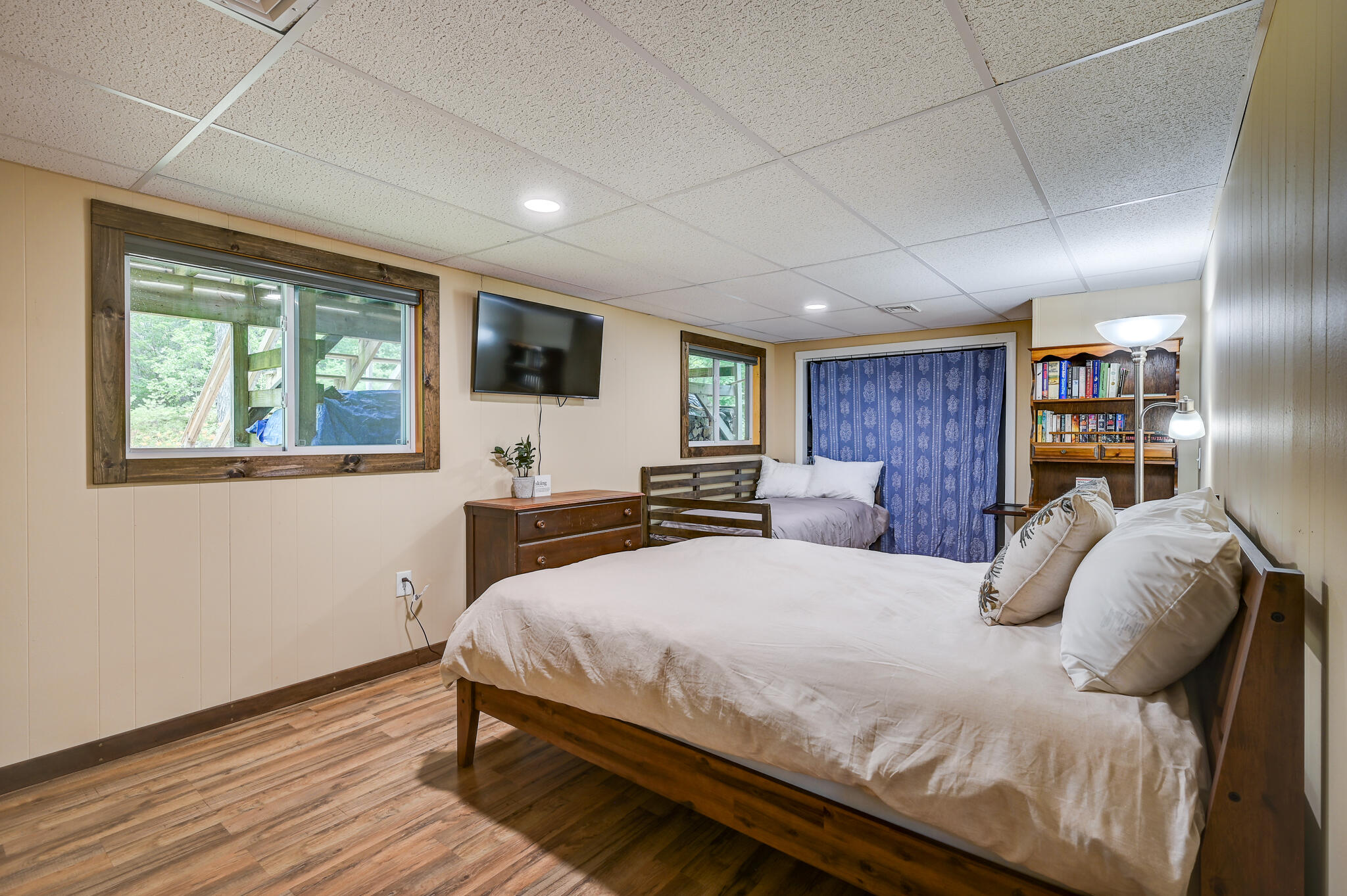 Bedroom with a large wood-framed bed, a second bed, and built-in bookshelves.