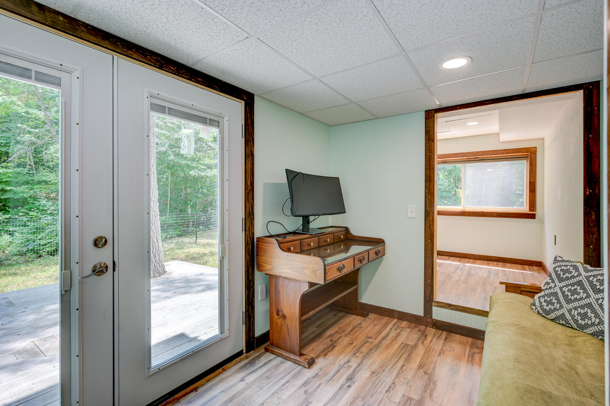 Interior room with a glass patio door, vintage wooden desk, monitor, and adjoining sitting area.