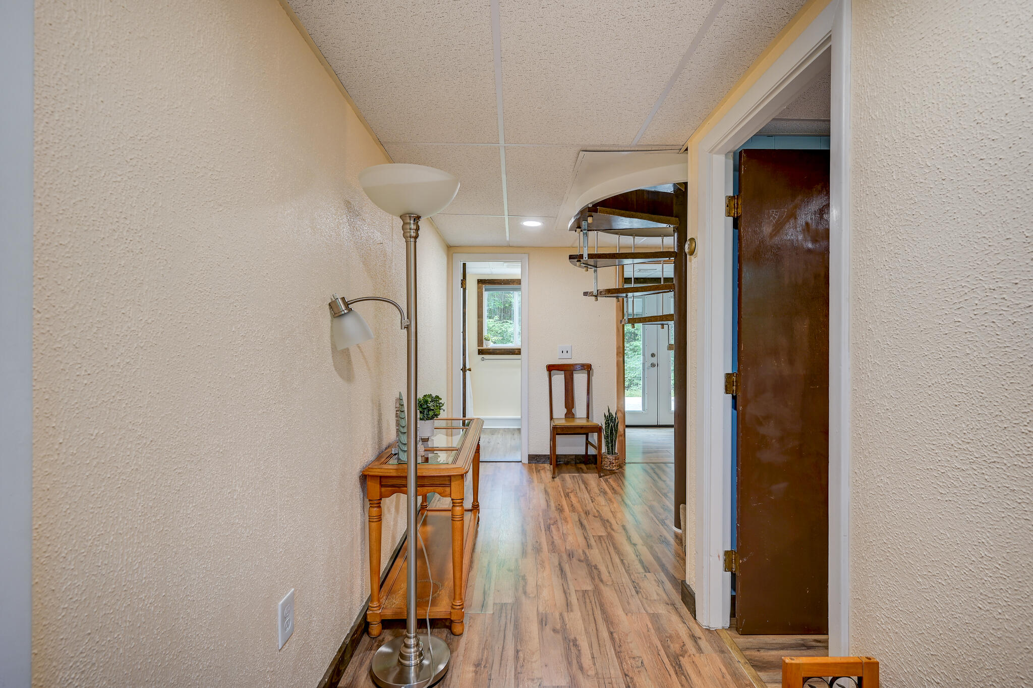 Hallway with wood-look flooring, a console table, floor lamp, and open doors.