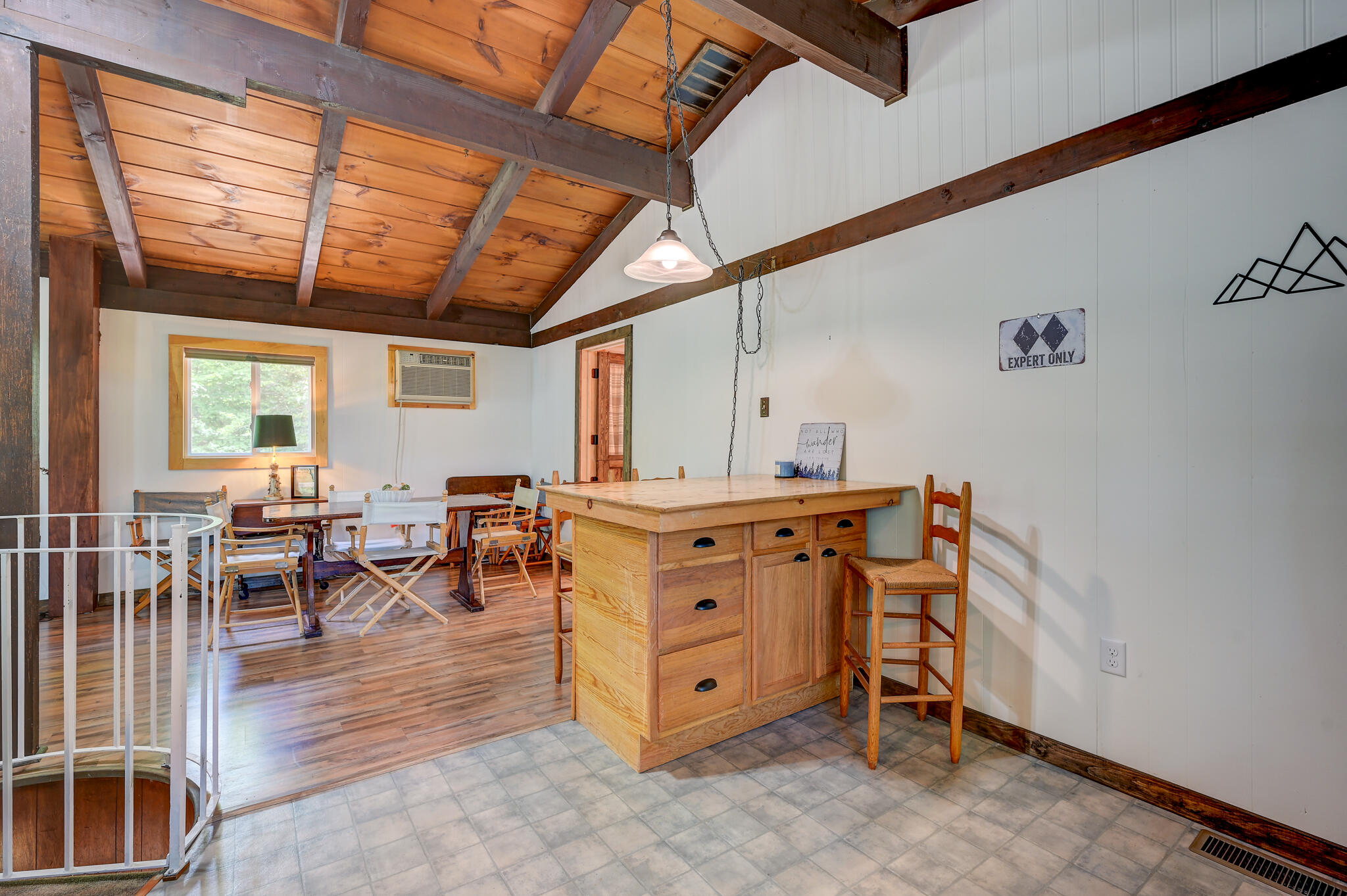 Kitchen and dining area with a wood island, exposed-beam ceiling, and spiral staircase.