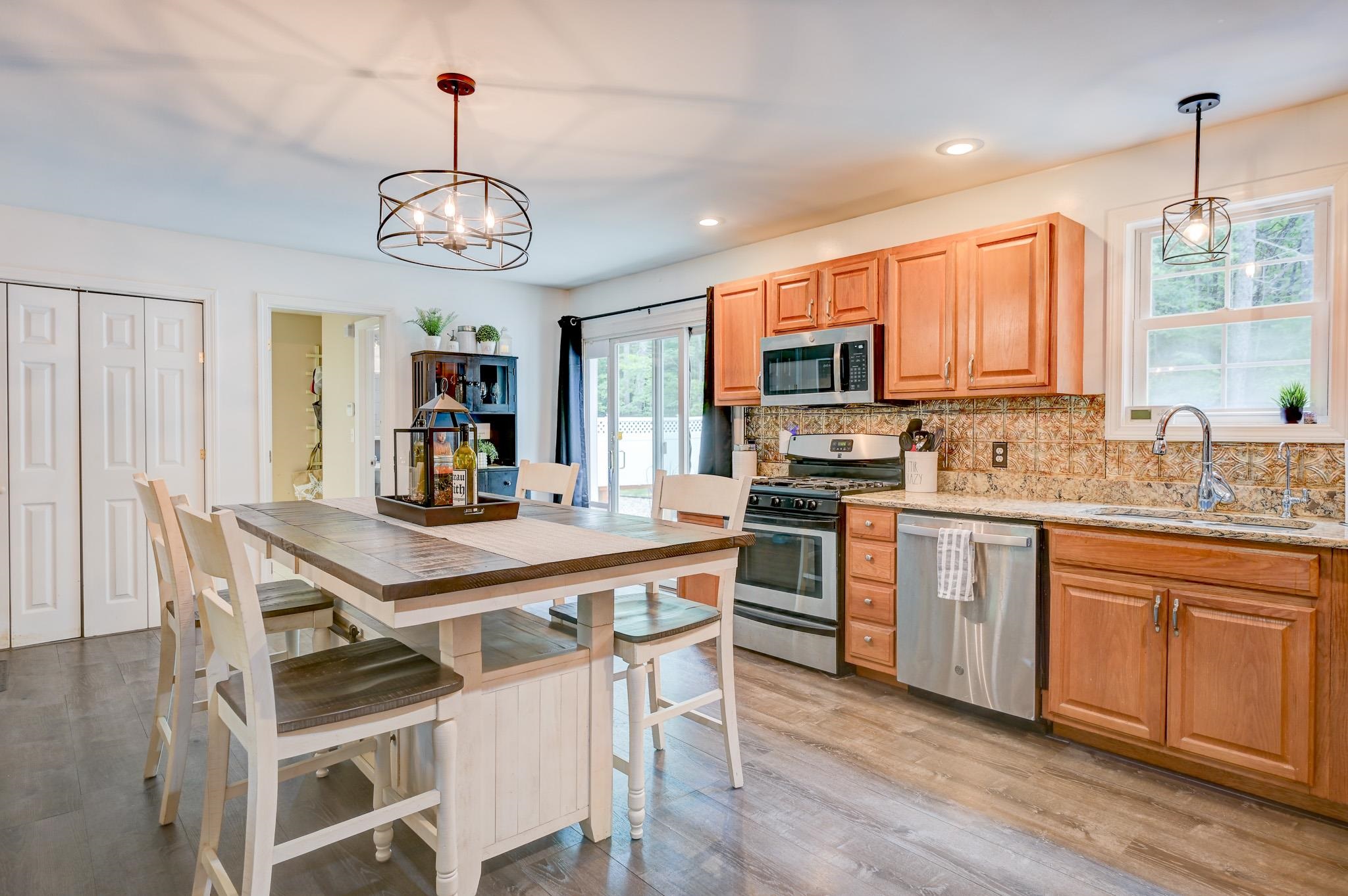 Kitchen with warm wood cabinets, patterned tile backsplash, stainless steel appliances, and a large island with seating.