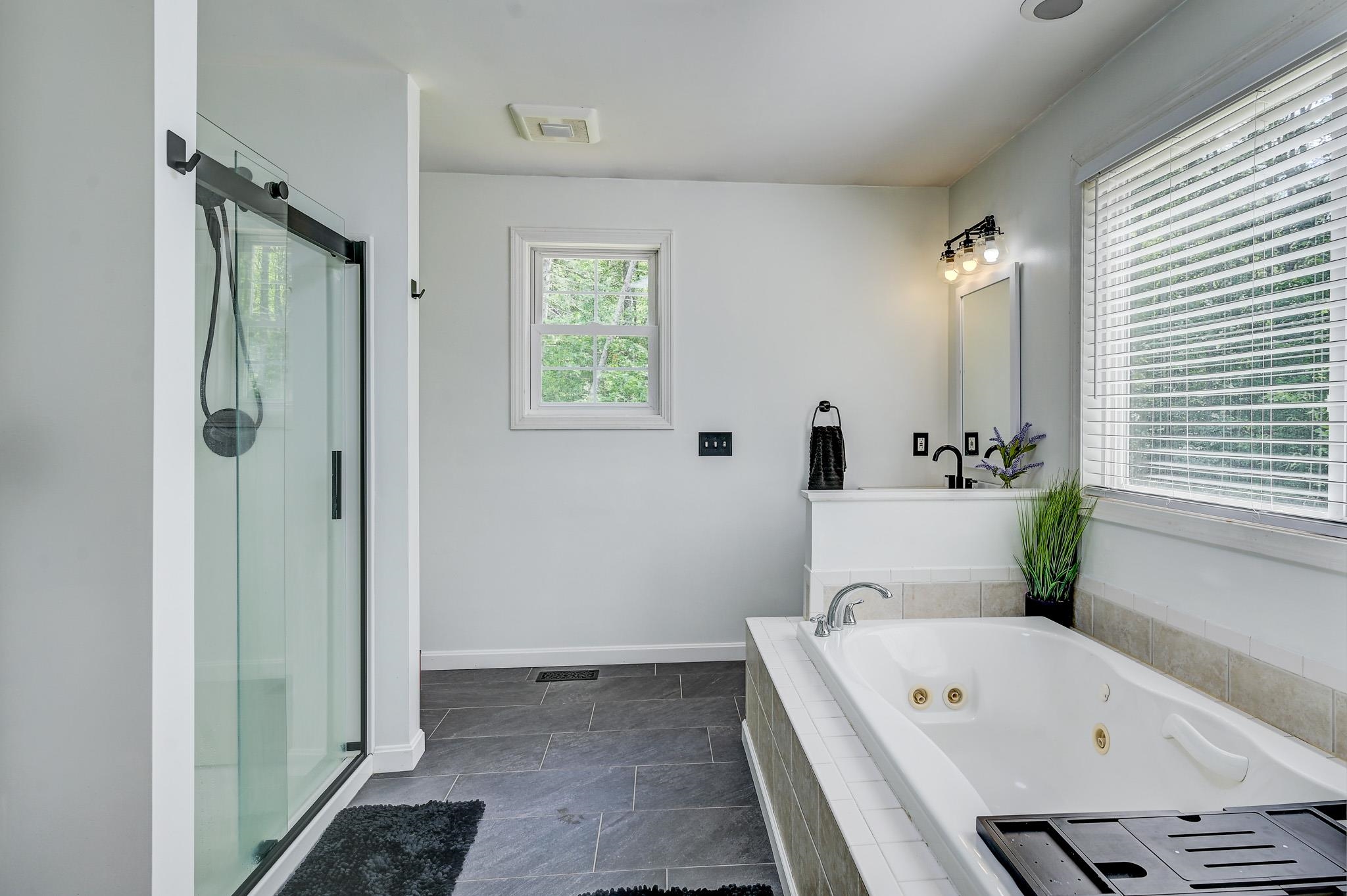 Bathroom with a glass shower and large jetted soaking tub beside a wide window.