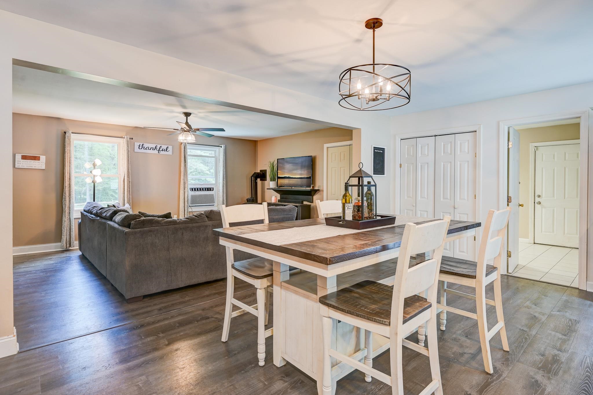 Open-plan living and dining room with a farmhouse-style table, gray sectional, and dark wood floors.