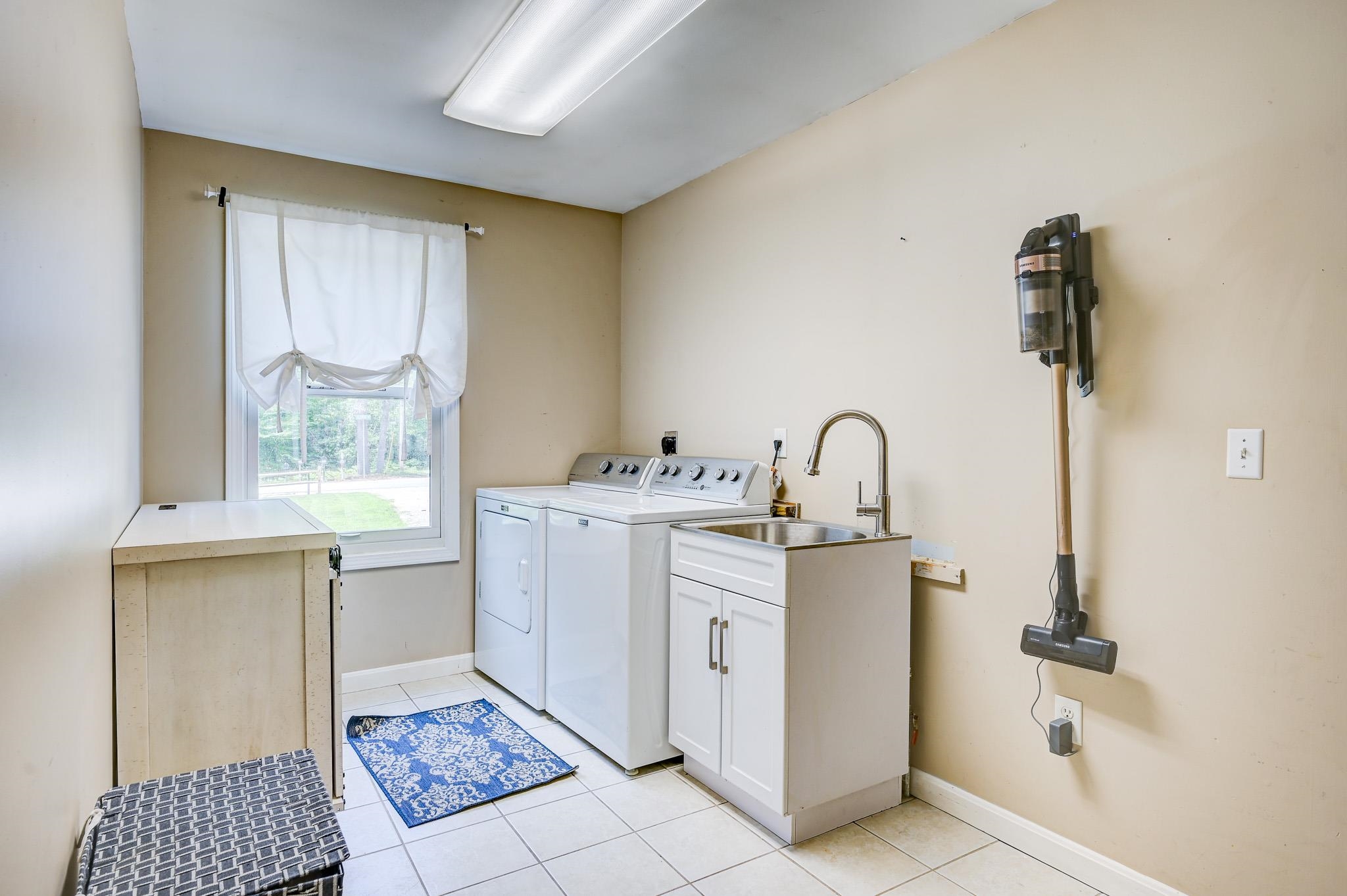 Laundry room with washer and dryer, utility sink, and tiled floor.