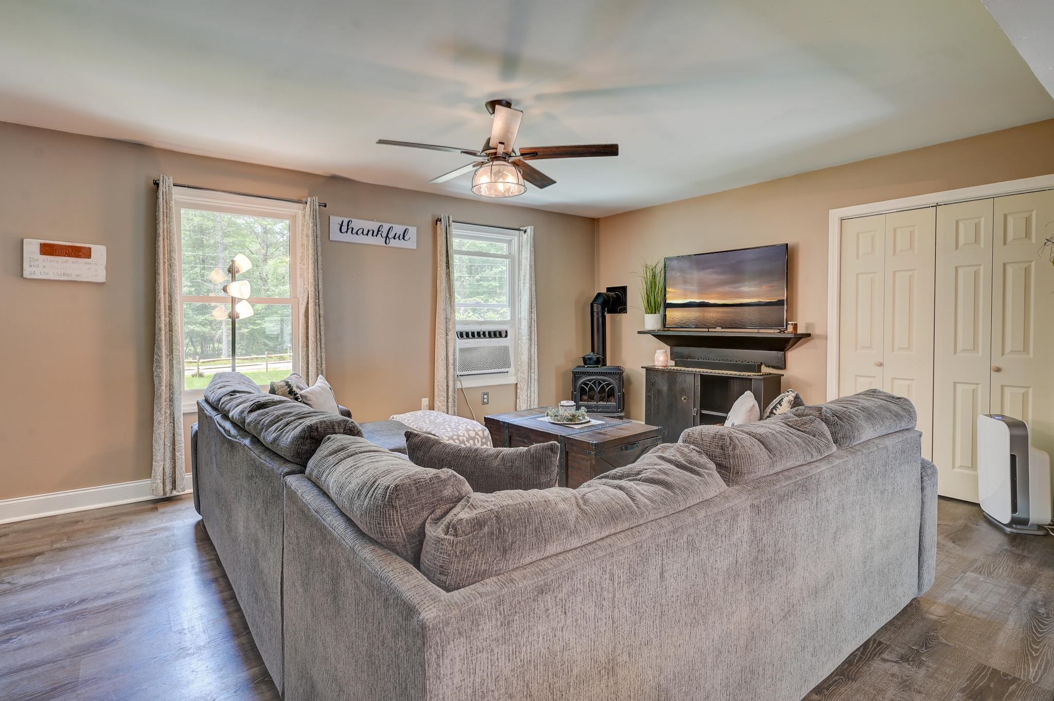Living room with a large gray sectional, wood stove, and TV above a cabinet.