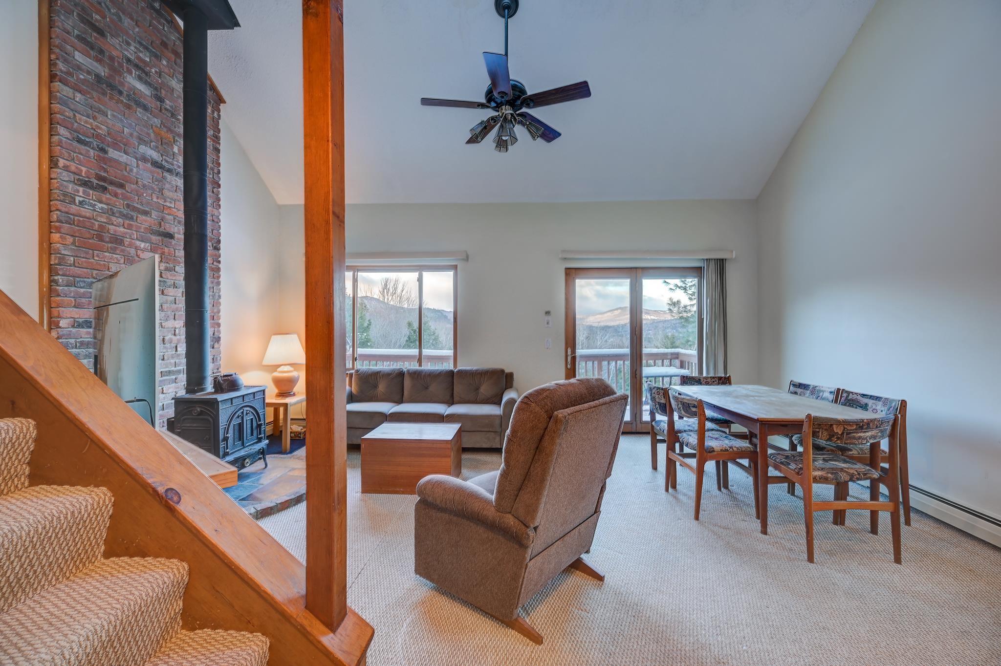 Open-plan living and dining room with a brick fireplace, wood stove, and mountain views.