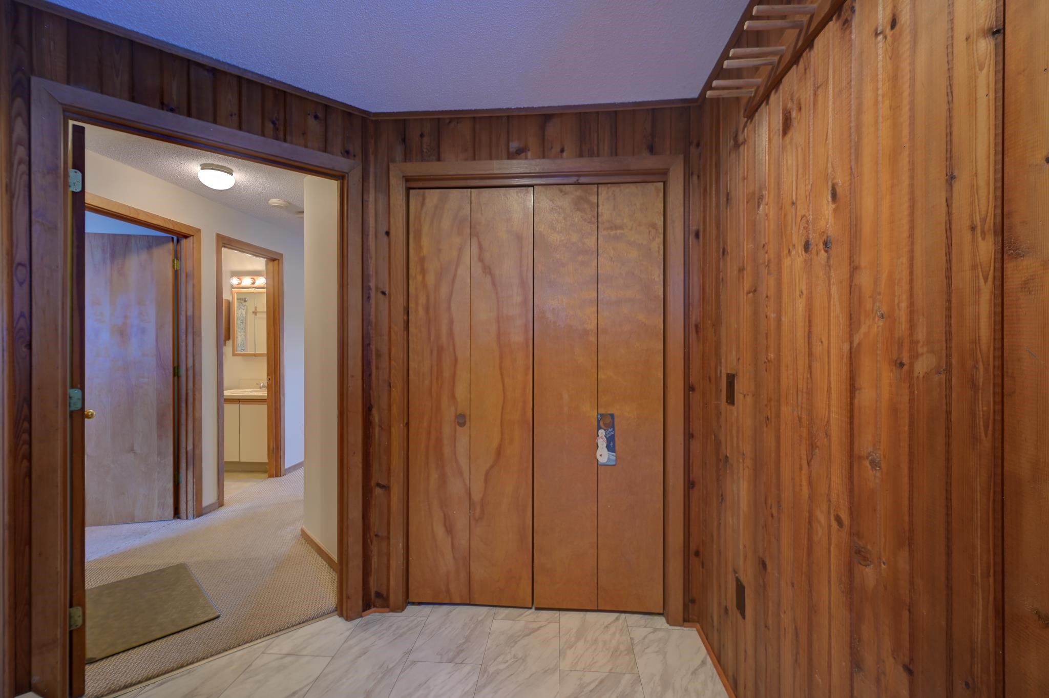 Wood-paneled entry with sliding closet doors and a tiled floor.