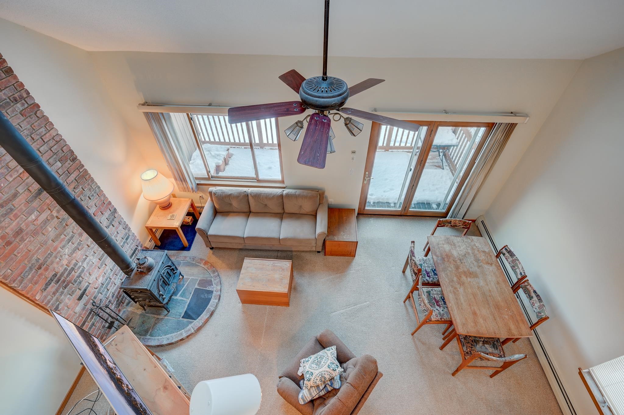 Living and dining room with a brick wood-stove hearth and sliding doors onto a snowy deck.