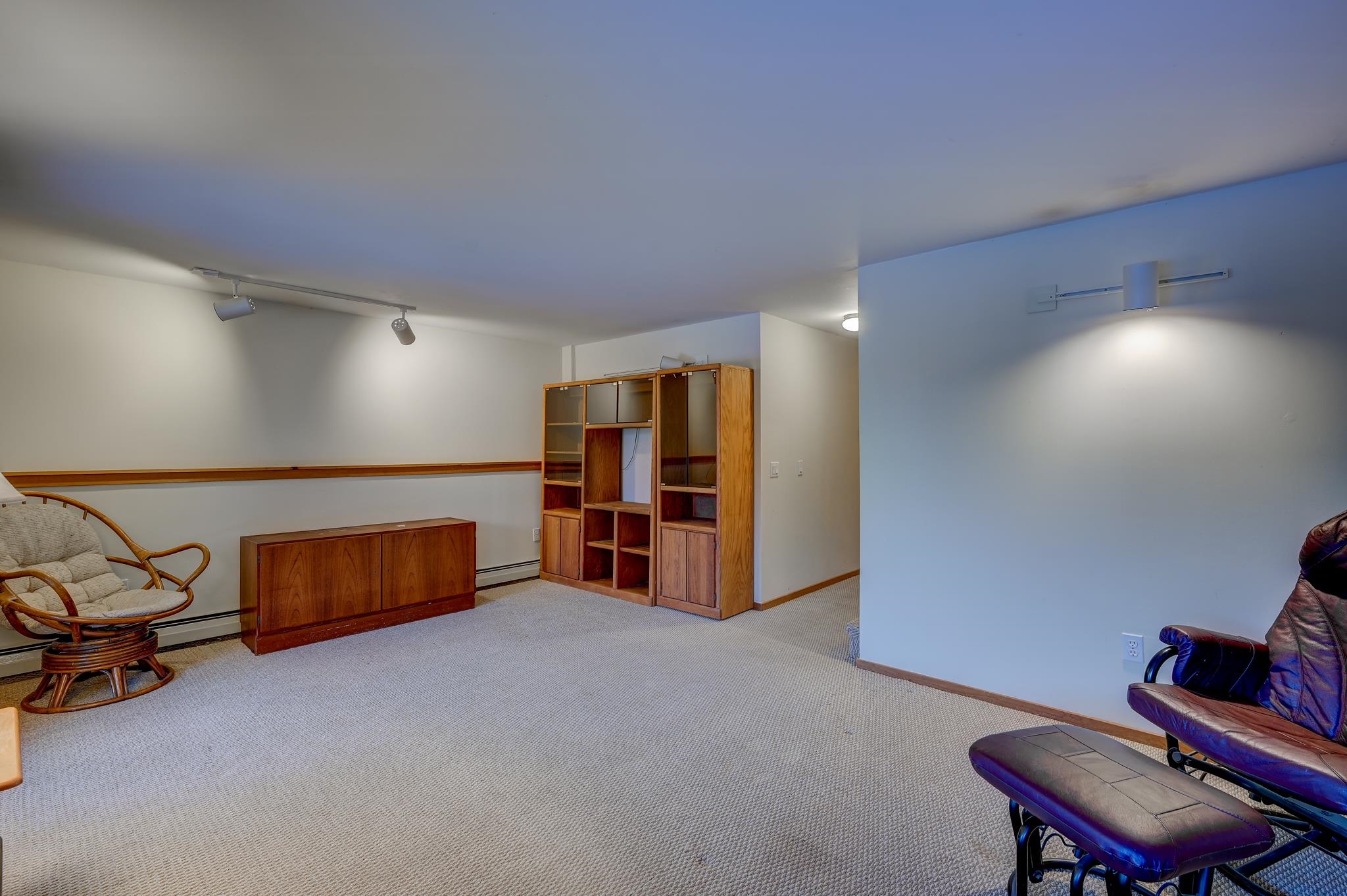 Furnished carpeted room with wood shelving and a leather lounge chair with ottoman.