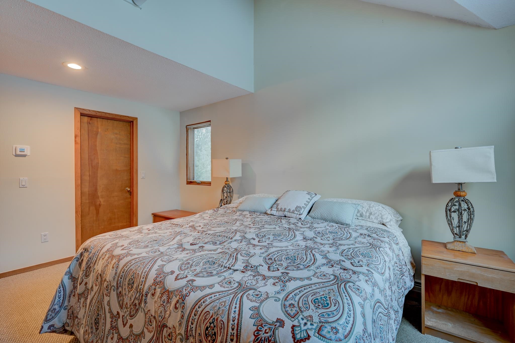 Bedroom with a paisley-patterned bedspread, matching bedside tables, and decorative lamps.