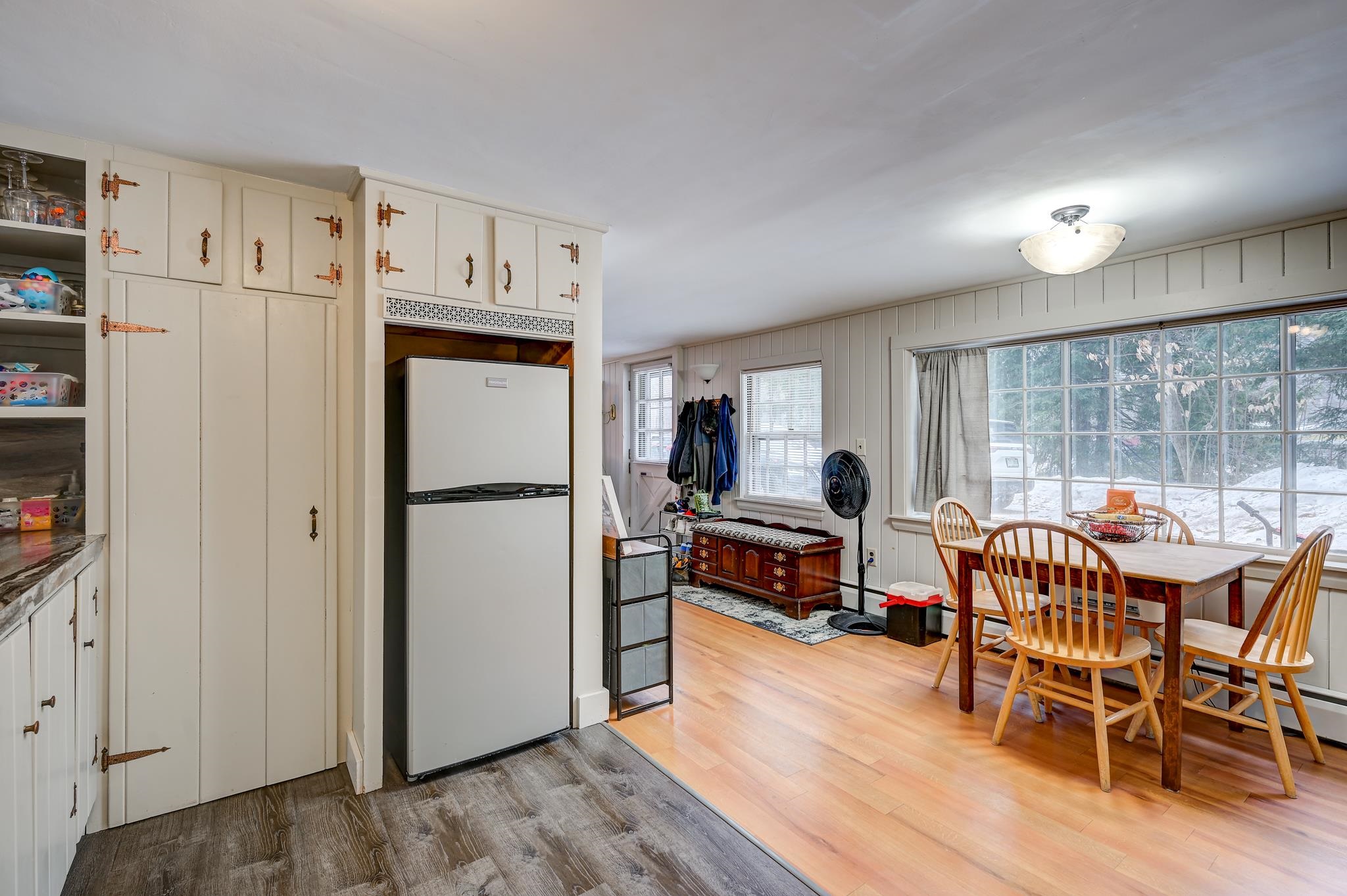 Kitchen and dining area with cream built-in cabinets, a wood table, and large windows overlooking snow.