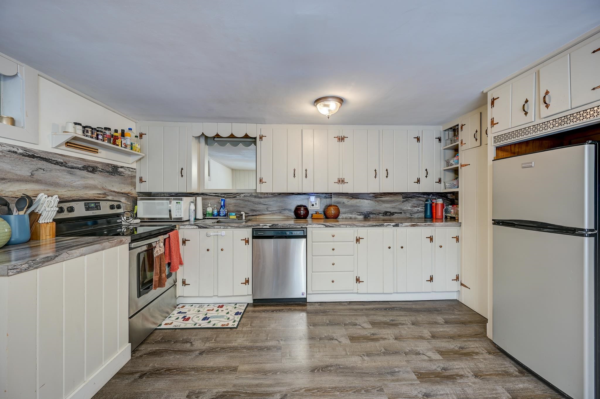 Kitchen with white cabinetry, gray stone counters, and stainless steel appliances.
